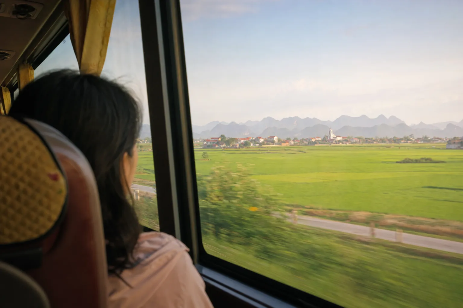 旅客坐在越南长途车内望向车窗外的乡野