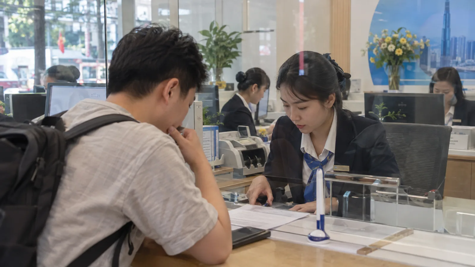 河内老城区清晨街道，临街骑楼店铺前一名戴斗笠的小贩推着装满鲜花的车走过