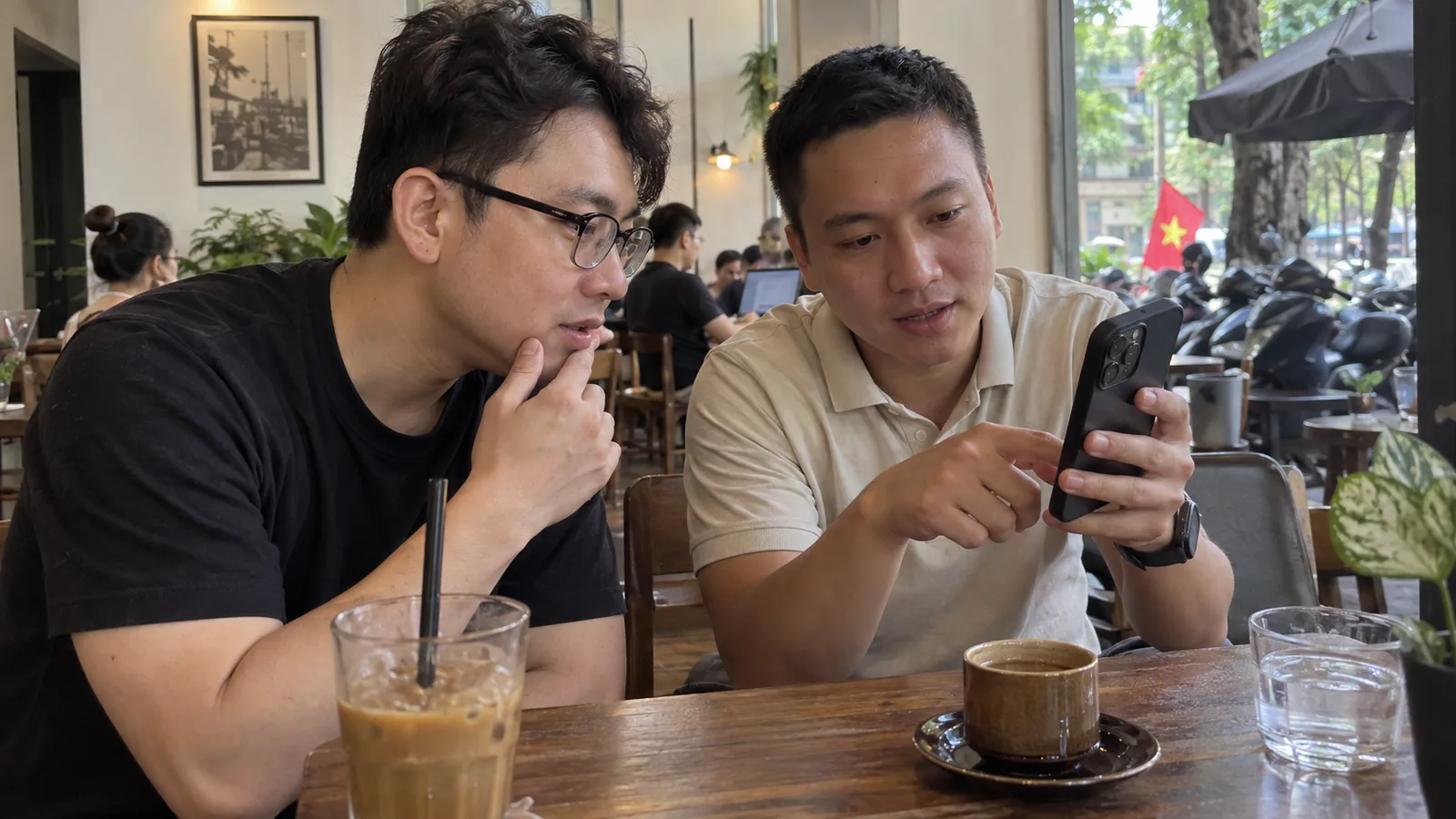 两名朋友在咖啡店讨论手机通讯应用的使用